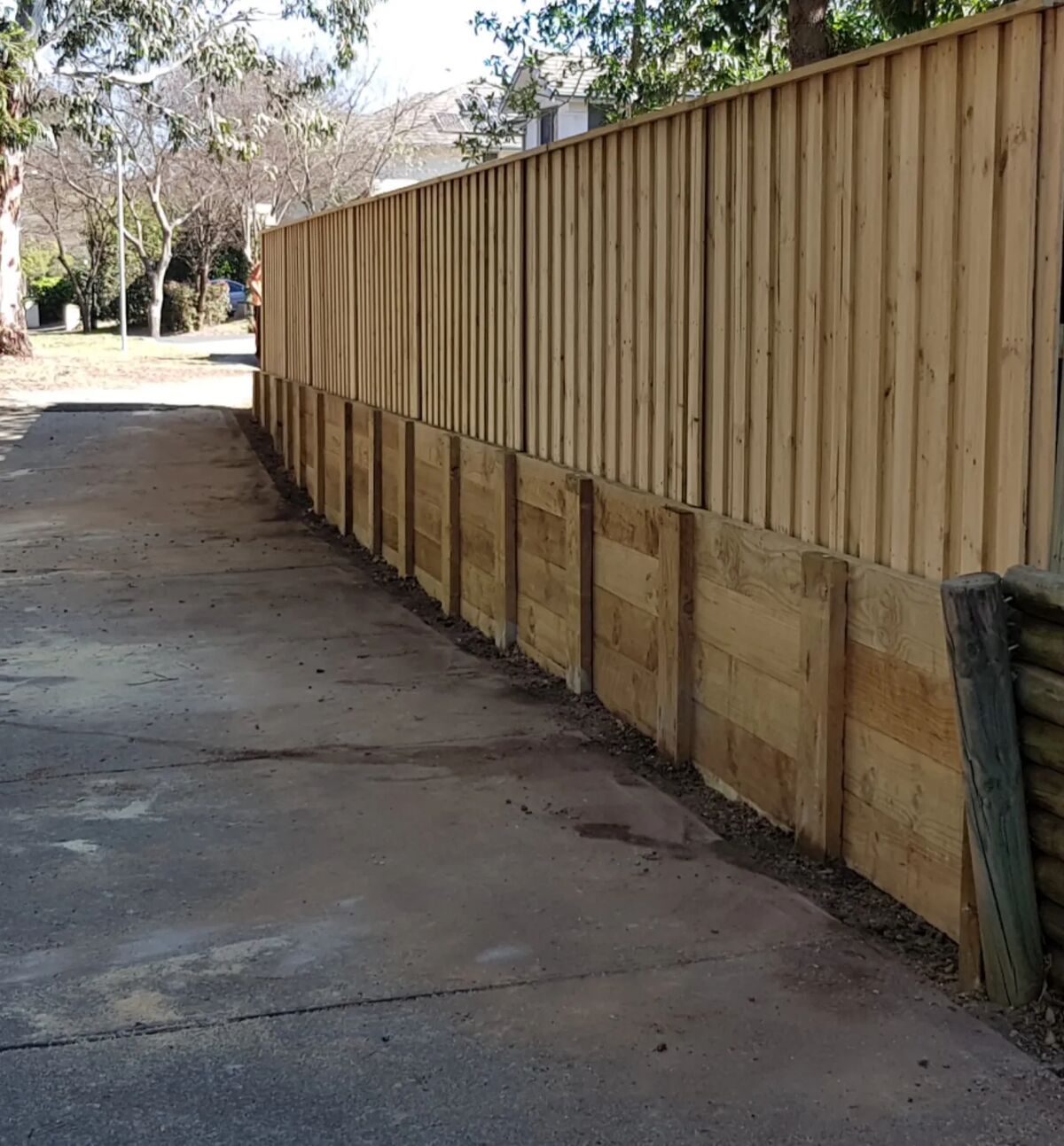 Timber paling fence with sleeper retaining along a driveway, built by Fresh Fencing